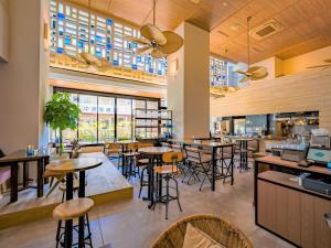 a restaurant with tables and chairs and windows at Tabino Hotel lit Miyakojima in Miyako Island