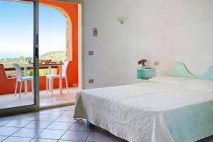 1 dormitorio con 1 cama y balcón con mesa en Residence Lu Nibareddu, Loiri, en Monte Petrosu