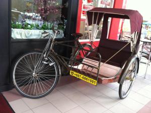 a bike parked next to a car with at Pontian Garden Hotel in Pontian Kecil