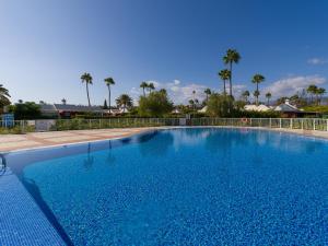 ein großer blauer Pool mit Palmen im Hintergrund in der Unterkunft Bungalow Maspalomas Leticia in Maspalomas