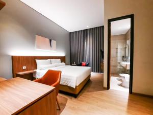a hotel room with a bed and a bathroom at Votel Krakatau Boutique Hotel Semarang in Semarang