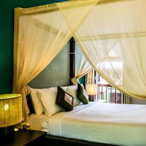 a bedroom with a canopy bed with curtains at The Village House in Santubong