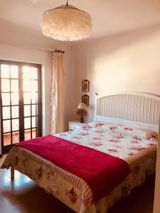 1 dormitorio con 1 cama grande con manta roja en Casa do Canto en Vila Nova de Milfontes