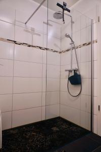 łazienka z prysznicem wyłożona białymi kafelkami. w obiekcie FEWO Sanddorn w mieście Hohen Wieschendorf