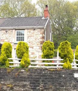a white fence in front of a brick house at 2-Bed Cottage in in Welsh Valley Nr Swansea in Swansea