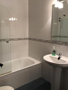 a white bathroom with a sink and a tub and a sink at Casa Rural las Escuelas II in Hoyo de Pinares