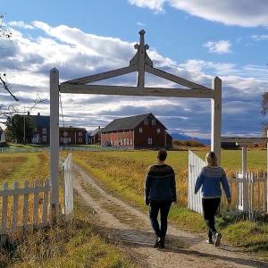two people walking down a dirt road through a gate at Tranøya in Tranøya