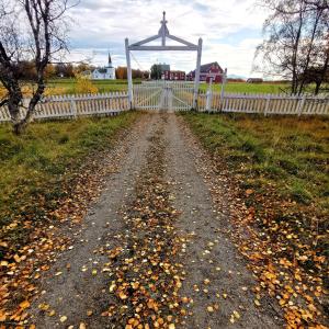 uma estrada de terra ao lado de uma cerca branca em Tranøya em Tranøya