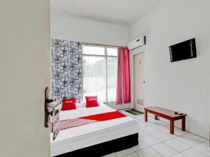 a bedroom with a bed with red pillows and a window at OYO 90621 Pondok 23 in Cilimus 2