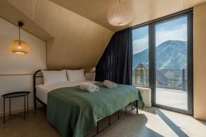 a bedroom with a bed and a large window at Kazbegi Targmani Cottages in Stepantsminda