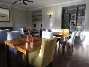 comedor con mesas y sillas de madera en Sani Pass Manor Guest House, en Himeville