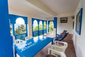 une table et des chaises bleues dans une pièce avec fenêtres dans l'établissement Seclude Ramgarh Arthouse, à Nainital