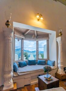 einen Fensterplatz in einem Zimmer mit blauen Kissen in der Unterkunft Seclude Ramgarh Arthouse in Nainital
