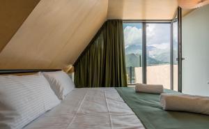 a bedroom with a large bed with a large window at Kazbegi Targmani Cottages in Kazbegi