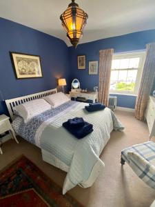 a bedroom with a large bed with blue walls at Awel y Mor in Beaumaris