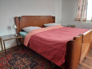 a bedroom with a bed with a red comforter and a table at Ferienwohnung Tymoshenko in Altenau