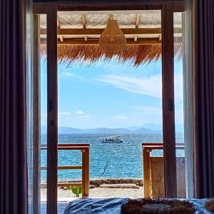 a bedroom with a view of the ocean from a window at VnS Beachfront Guesthouse in Nusa Penida