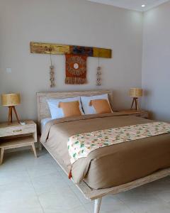 a bedroom with a large bed and two tables at VnS Beachfront Guesthouse in Nusa Penida
