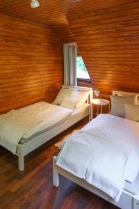 two beds in a room with wooden walls at Waldhäuschen am Sonnenhof in Kassel