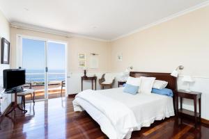 een witte slaapkamer met een bed en uitzicht op de oceaan bij Home2Book Stunning Villa Raquel, Pool & View in Sauzal