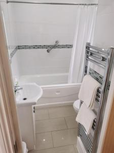a white bathroom with a sink and a bath tub at Old Bull Inn in Royston
