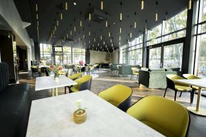 a restaurant with tables and chairs and windows at Oginski Hotel in Plungė