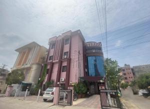 齋浦爾的住宿－Hotel Aarjee Crescent Jaipur，一座粉红色的建筑,前面有一辆汽车