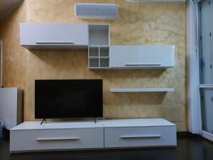 una sala de estar con TV en un centro de entretenimiento blanco en Milano Malpensa Grandi Mansarda Attico, en Gallarate