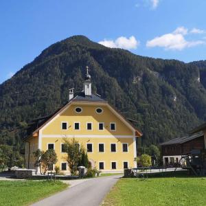 a large yellow building with a mountain in the background at Pfarrhofbauer in Sankt Martin bei Lofer