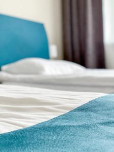 1 cama con sábanas blancas y manta azul en "AVA" apgyvendinimo įstaiga en Vilna