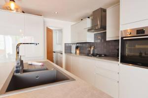 a kitchen with white cabinets and a sink at Hotwells Modern Mews in Bristol