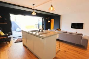 eine Küche und ein Wohnzimmer mit einem Waschbecken und einem Sofa in der Unterkunft Hotwells Modern Mews in Bristol