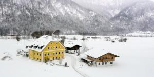 a yellow building in the snow with mountains in the background at Pfarrhofbauer in Sankt Martin bei Lofer