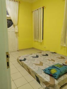 a room with a large bed in a yellow room at Villa Wubao Kota Bunga 3 Kamar Harga Budget in Cinengangirang