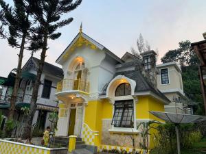 a yellow and white house with a balcony at Villa Wubao Kota Bunga 3 Kamar Harga Budget in Cinengangirang