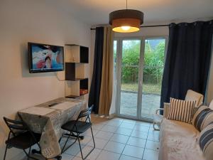 ein Wohnzimmer mit einer Couch, einem Tisch und einem Fernseher in der Unterkunft L'escale honfleuraise in Honfleur