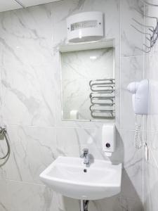 a white bathroom with a sink and a mirror at "AVA" apgyvendinimo įstaiga in Vilnius