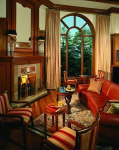 een woonkamer met een rode bank en een open haard bij Wildflower Hall, An Oberoi Resort, Shimla in Shimla