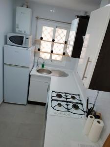 a white kitchen with a sink and a stove at Vistal al mar Palasiet in Era de Soler