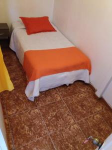 Dormitorio pequeño con cama con manta naranja en Hostal Vicmar, en Viña del Mar