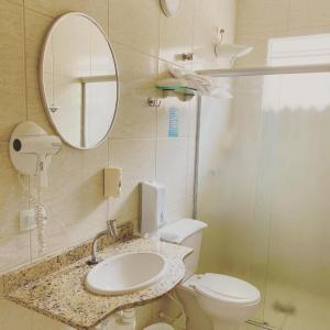 a bathroom with a sink and a toilet and a mirror at Hotel Village Campinas in Campinas