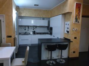 cocina con encimera negra y 2 taburetes en Milano Malpensa Grandi Mansarda Attico, en Gallarate