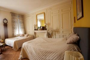 a bedroom with two beds and a mirror at L'Antre de Gadag in Forges-les-Eaux