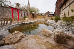 a small pond in a yard with rocks at L'Antre de Gadag in Forges-les-Eaux