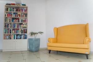 a yellow chair in a room with a book shelf at Sunrise Hotel in Karpathos