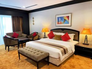 a hotel room with a large bed and a chair at Grand Darul Makmur Hotel Kuantan in Kuantan