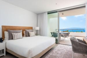 a bedroom with a large white bed and a balcony at Los Jardines de Abama Suites in Guía de Isora