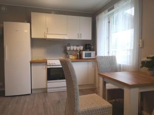 a kitchen with white cabinets and a table with chairs at Norra NY Hostel in Stöllet