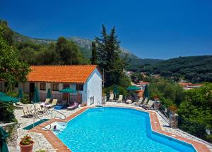 a swimming pool in front of a house at Magda's Hotel Apartments in Parga