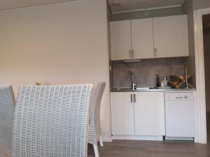 a kitchen with white cabinets and two chairs and a sink at Norra NY Hostel in Stöllet